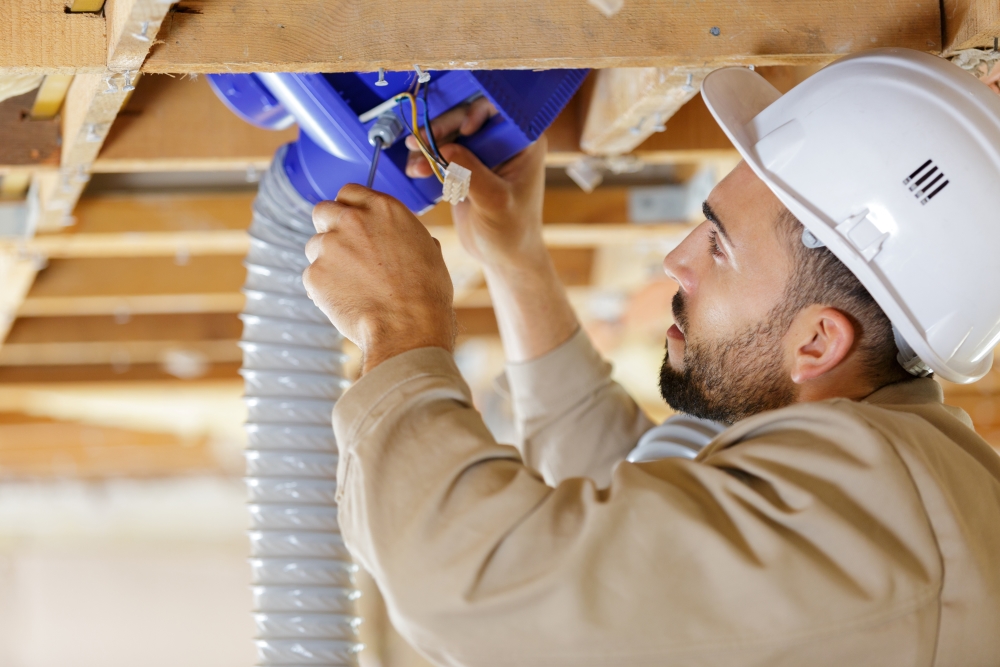 Technicien HVAC installant des éléments d’un système de climatisation dans un comble – Chauffagiste / Clim / PAC 64