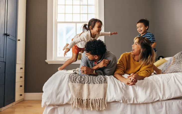 Une famille joue allongée sur un lit
