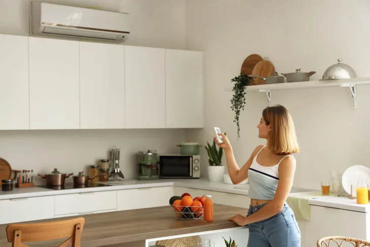 Femme qui allume sa VMC dans la cuisine