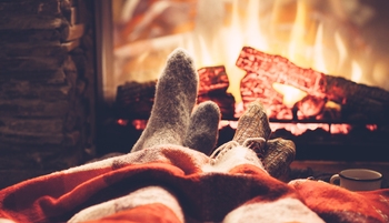 Des jambes avec des chaussettes et un plaid devant les flammes d'une cheminée