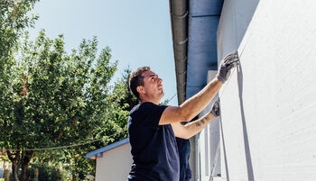 Artisan pose un bloc d'isolant sur un mur extérieur