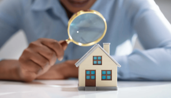 homme qui tient une loupe devant une maison