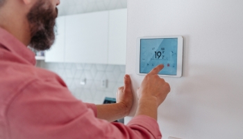 Un homme règle la température sur un thermostat