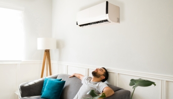 homme sur son canapé en dessous d'une climatisation 