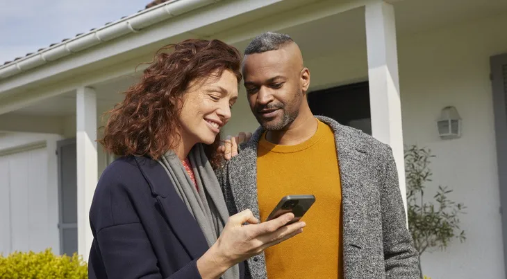 couple devant la maison sur le téléphone